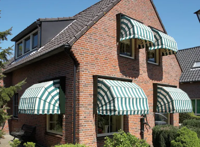 Gestreepte markiezen boven de ramen van een bakstenen pand