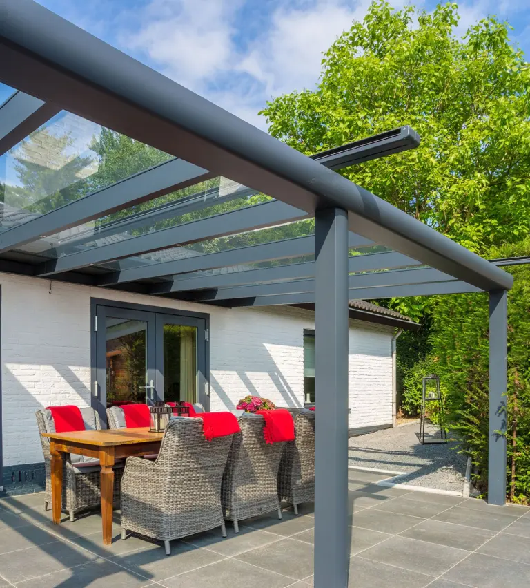 Overkapping met glazen dak boven een terras met tafel en stoelen